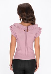 Lilla ribbet top med flæser på ærmerne og en bindedetalje bagpå. Stoffet har en blød tekstur og et tætsiddende design.