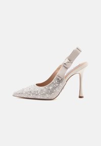 Beige slingback-pumpit, jolla on terävä kärki, koristeltu kristalleilla ja helmillä. Omistaa teksturoidun nauhaaksentin ja korkean stilettokannan.