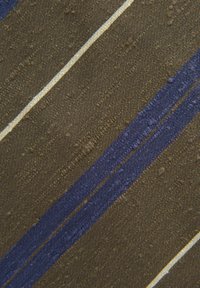 Textiel met een gestructureerde, olijfgroene basis en opvallende blauwe en gele strepen. Het oppervlak heeft verhoogde, onregelmatige patronen die diepte toevoegen.