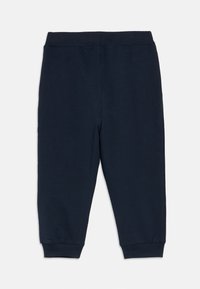 Granatowe bawełniane spodnie dresowe z prążkowanym paskiem w talii i ściągaczami przy nogawkach, cechujące się gładką teksturą i zwężanym krojem.