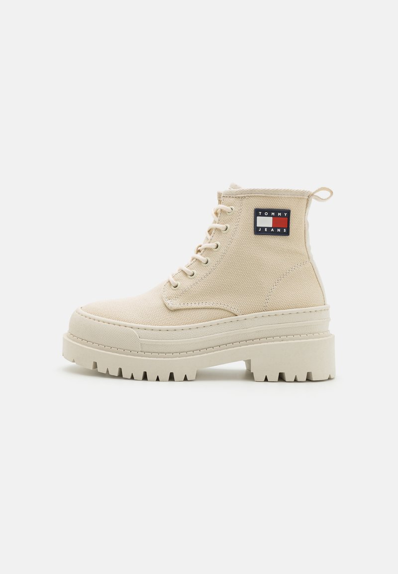 Beige kanvas høj-top støvle med kraftig skridsikker sål, snørebånd foran, en lille hæksløjfe og Tommy Jeans logo patch på anklen.
