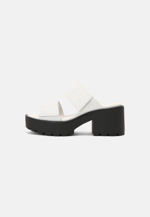 Witte open teen mule sandaal met twee brede bandjes en een dikke zwarte chunky plateauhak met grof profielzool.