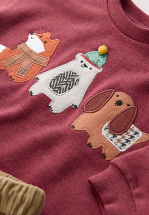 Burgundia punutud kampsun, millel on kolm tikitud looma: salli kandev rebane, rohelist mütsi kandev põhjapõder ja mustriga kaunistatud pruun koer.