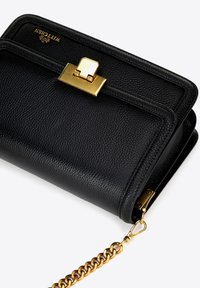 Borsa a mano in pelle nera con texture a grana, chiusura in tonalità oro e tracolla a catena. Presenta un design strutturato e un logo visibile sulla patta.
