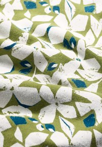 Baumwollstoff mit einem abstrakten Blumenmuster in Weiß und Blau auf grünem Hintergrund, mit einer strukturierten Oberfläche und leichtem Fall.