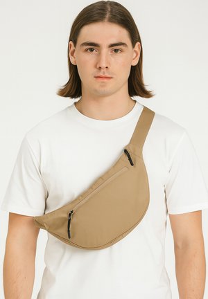 Beige Umhängetasche aus wasserabweisendem Material, mit zwei Reißverschlusstaschen und einem verstellbaren Tragegurt. Glatte Textur und minimales Design.