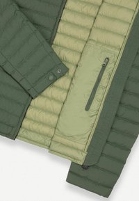 Vuorattua takkia, jossa on tumma vihreä ulkopinta ja vaalean vihreä sisäpinta, ommellut paneelit, nepparit ja vetoketjukiinnitys sekä sivutasku.