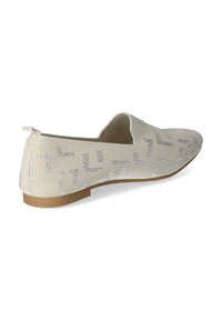 Zapato deslizante beige con parte superior de tela texturizada, adornado con embellishments plateados en un patrón geométrico. Tacón plano con suela de contraste.