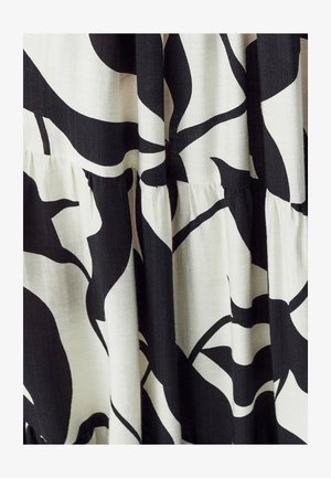 Tessuto bianco e nero con un ampio motivo floreale, caratterizzato da una superficie testurizzata e dettagli arricciati all'orlo.