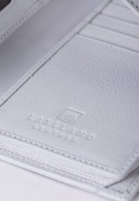 White leather wallet with a textured finish, featuring a zip closure and embossed "Lakeland Leather" logo. Multiple card slots visible.