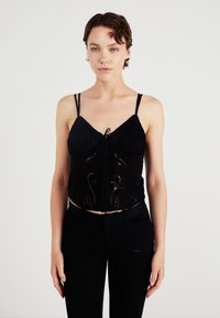 Svart avkortet topp med tynne stropper, med broderte detaljer og knappelukking foran. Materialet ser glatt ut med en svakt teksturert overflate.