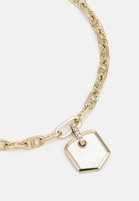 Collana in oro con maglie intrecciate, dotata di un pendente a forma esagonale accentuato da strass e una superficie liscia e lucida.