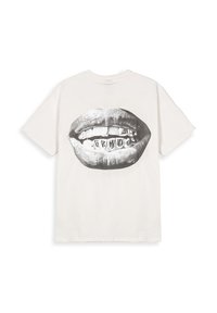 Camiseta blanca de algodón con un gráfico de labios con rejas dentales de metal impresas en negro y gris en la parte posterior. Corte relajado, mangas cortas.