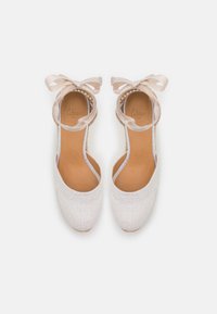 Espadrillas beige chiaro con tomaia in tessuto testurizzato, lati aperti e un nastro decorativo alla caviglia. Soletta in pelle liscia.