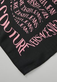 Fekete selyemsál, amelyen örvényló rózsaszín szöveg található, rajta a "Versace Jeans" és a "Couture" feliratokkal. Sima textúra, éles, foszforeszkáló betűkkel.