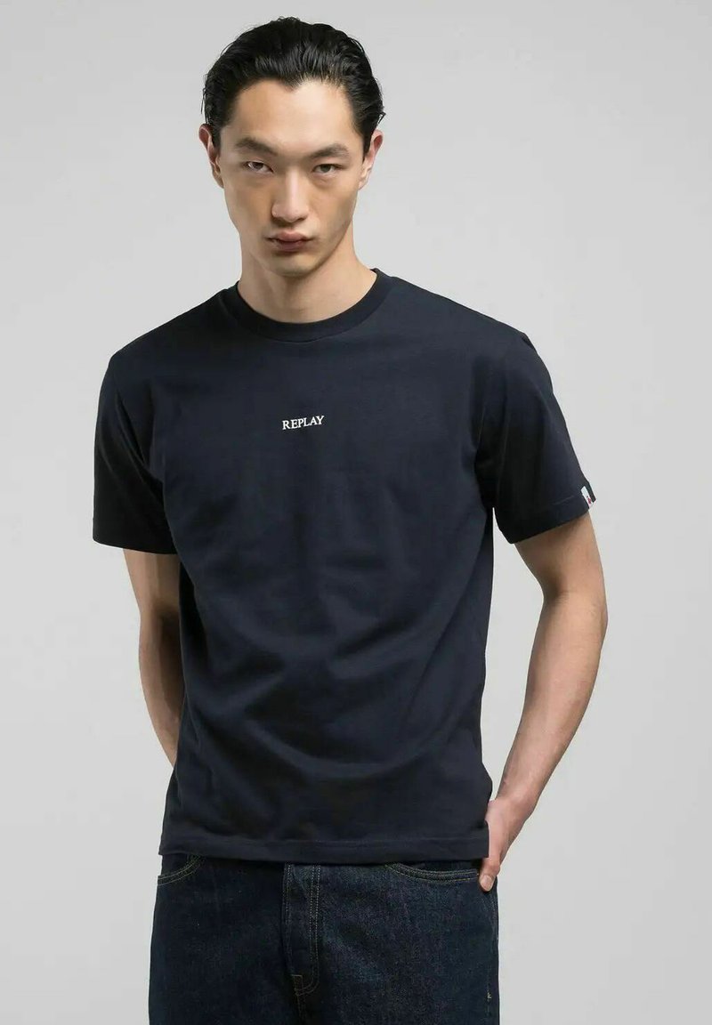 T-shirt di cotone blu navy con collo a giro, maniche corte e logo bianco "REPLAY" stampato sul davanti. Vestibilità classica con una texture liscia.