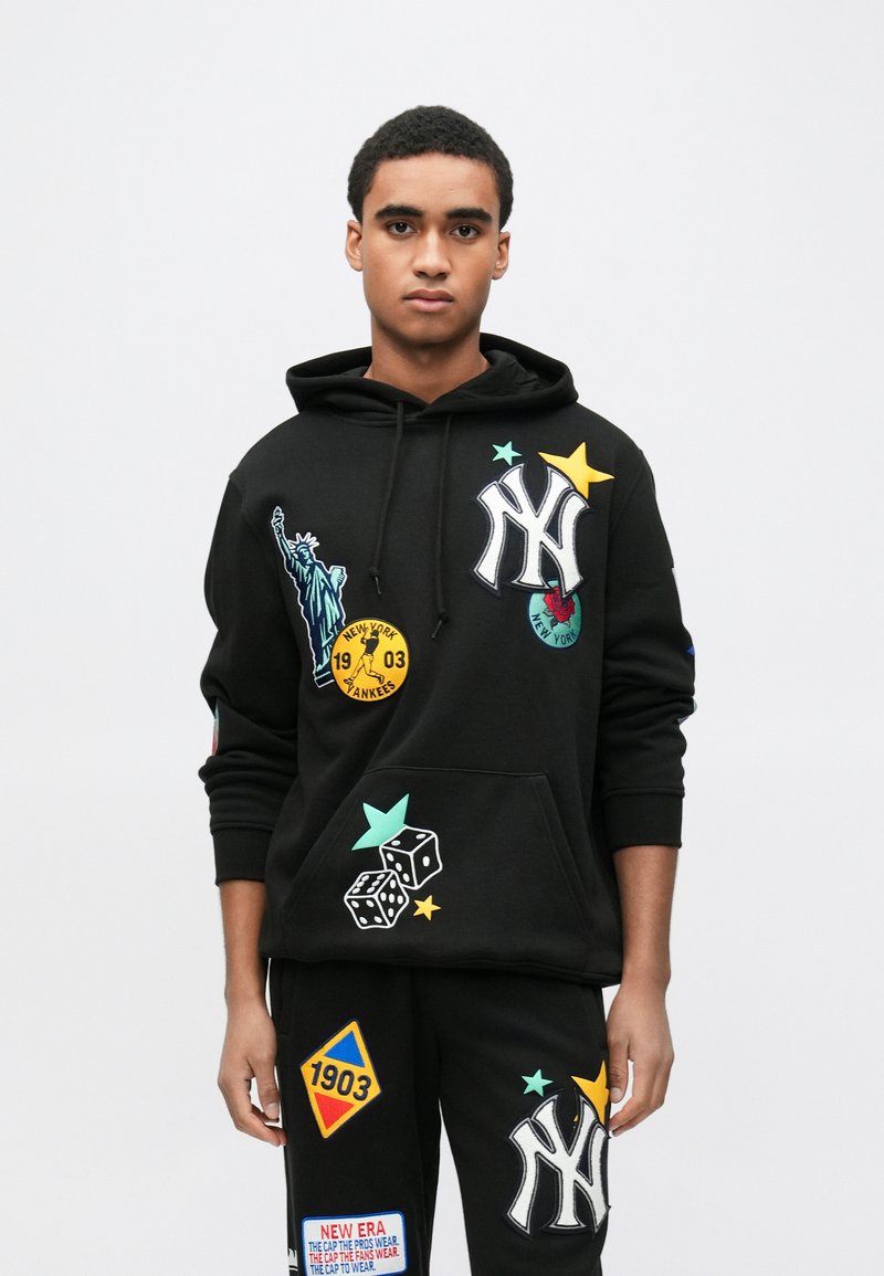Czarna bluza z kapturem z haftowanym logo New York Yankees, kolorowymi naszywkami, w tym Statua Wolności, gwiazdy i kości do gry. Konstrukcja z kieszenią typu kangur.