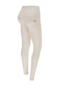 Beige leggings med bred midjebånd, med to baklommer med gullfargede detaljer. Glatt stoff med en elastisk, tettsittende design.