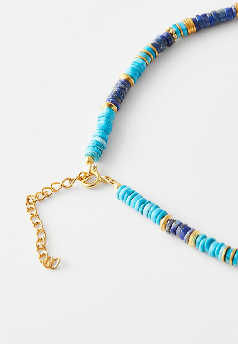 Perlenhalskette mit Türkis- und Lapislazuli-Perlen sowie goldenen Akzenten. Enthält eine Goldkette und einen Karabinerverschluss.