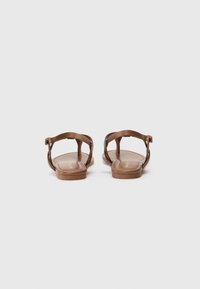 Bruna platta sandaler med tunna remmar, med en spänne detalj, slät textur och en minimalistisk design. Sålarnas färg är en ljusare brun.