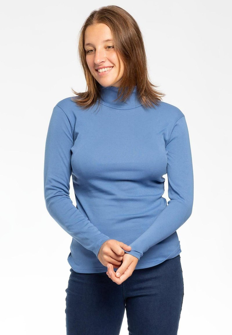 Maglione a maniche lunghe blu con collo alto realizzato in materiale morbido ed elastico, caratterizzato da un design aderente e maniche a cuffia. Abbinato a jeans scuri.