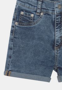 Shorts de mezclilla en azul oscuro con un ligero desgaste. Presentan un dobladillo doblado, cuatro bolsillos, herrajes plateados y costuras en contraste para un mayor detalle.