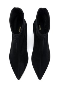 Bottines noires à bout pointu en daim doux, avec un design supérieur sans couture et un style enfiler. Matériel minimal avec une marque intérieure.