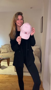 Ροζ καπέλο μπέιζμπολ με ένα μικρό λογότυπο που απεικονίζει κόκκινες, λευκές και μπλε ορθογώνιες μορφές· βαμβακερό υλικό, καμπυλωτό γείσο και ρυθμιζόμενο λουρί.