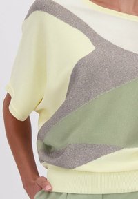 Gebreide trui in lichtgeel, met een geometrisch patroon in groen en metallic grijsaccenten, geribbelde zoom en korte mouwen.