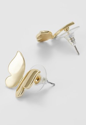 Gouden vlindervormige oorstekers met zilverkleurige pennen en doorzichtige plastic achterkantjes op een witte achtergrond.