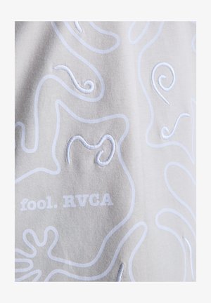 Lichtgrijze stof met witte geborduurde krullen en de tekst "fool. RVCA" onderaan, met nadruk op textuur en gedetailleerd ontwerp.