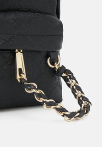 Bolso negro texturizado con una correa trenzada con detalles dorados y un cierre de cremallera dorada con detalle de logotipo.