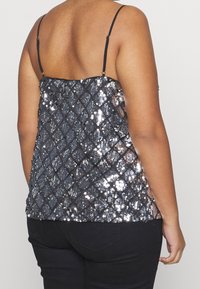 Zwarte pailletten top met een diamantpatroon, dunne verstelbare bandjes en een getailleerd ontwerp. Textuuroppervlak met reflecterende pailletten.