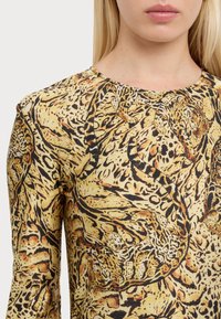 Långärmad tröja med ett gult och svart djurtryck. Mjuk textur med rund halsringning och figursydd passform.