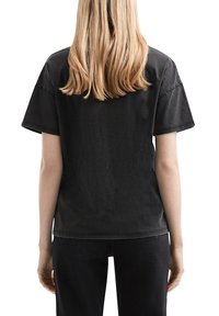 Schwarzes T-Shirt mit kurzen Ärmeln aus weicher Baumwolle, mit lässigem Schnitt, Rundhalsausschnitt und minimalen Nähdetails.