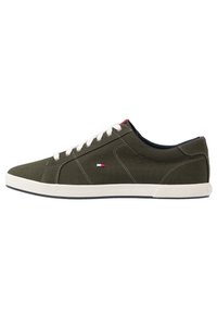 Gröna canvas låga sneakers med vita snören och sula, med en lågprofil design och röda, vita och blå logoprydnader.