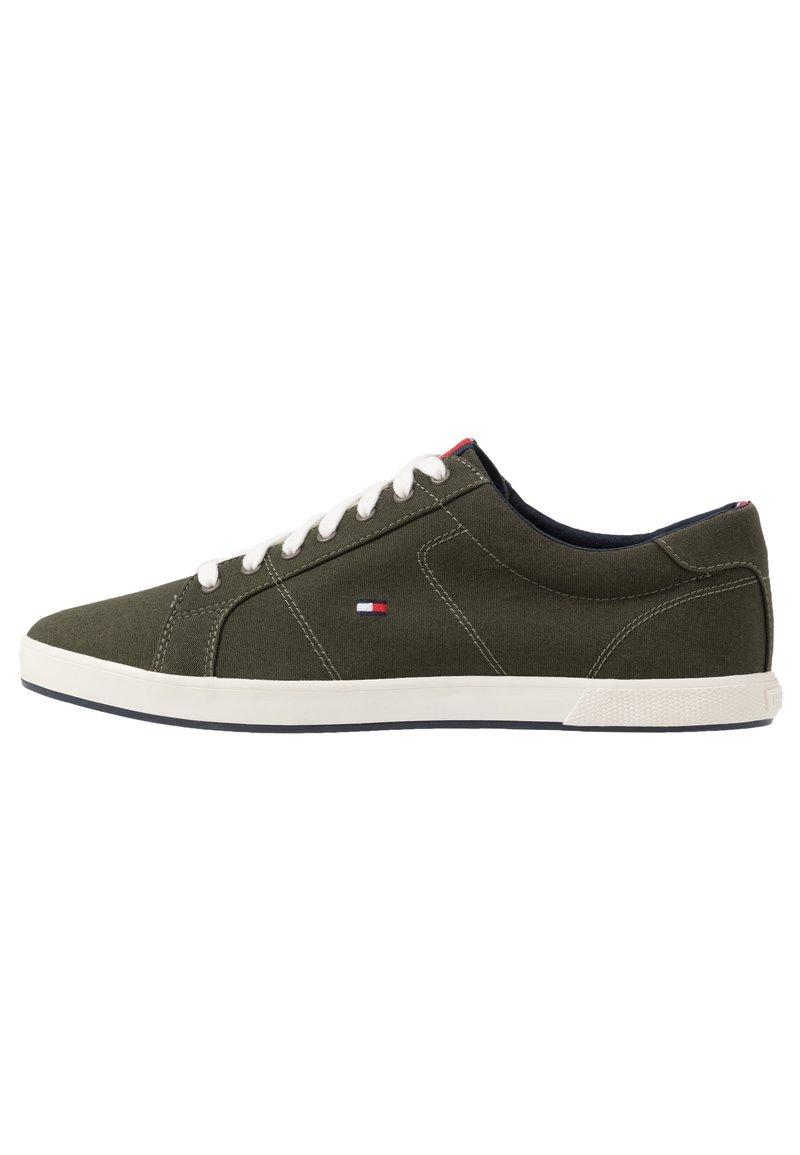 Gröna canvas låga sneakers med vita snören och sula, med en lågprofil design och röda, vita och blå logoprydnader.