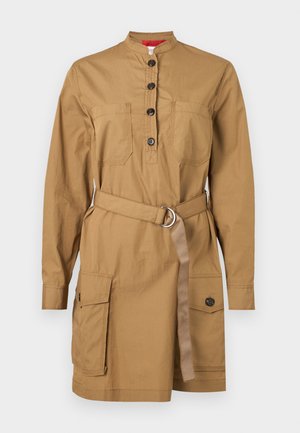 Beige Utility-Kleid mit hohem Kragen, Knopfleiste, Brusttaschen, tailliertem Gürtel und zwei Seitentaschen. Hergestellt aus einem leichten Stoff.