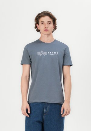 Graues Baumwoll-T-Shirt mit kurzen Ärmeln und Rundhalsausschnitt. Mit einem weißen Logo-Druck "ALPHA INDUSTRIES", der auf der Brust zentriert ist.