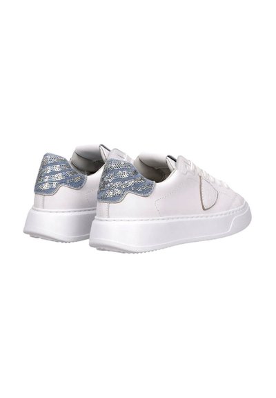 Zapatillas de cuero blancas con una suela blanca gruesa y un acento brillante de lentejuelas azules en el talón. Diseño clásico con cordones.