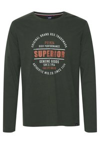 Langærmet mørkegrøn t-shirt lavet af bomuld, med et cirkulært grafisk motiv med teksten "SUPERIOR" i rød og hvid. Rund halsudskæring.