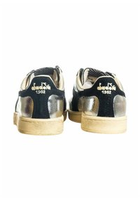 Zwarte en zilveren sneakers met een gestructureerde afwerking, voorzien van een tan kleurige zool. Reflecterende panelen en een merkaccent op de hak.