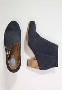 Granatowo-niebieskie zamszowe botki za kostkę z masywnym, teksturowanym drewnianym obcasem, z bocznym zamkiem błyskawicznym i zaokrąglonym noskiem.