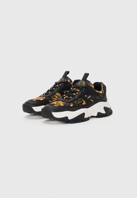 Black and orange patterned sneakers with a chunky white midsole, textured black outsole, and black laces, featuring a pull tab on the heel.