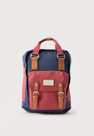 Συμπαγής σακίδιο με ύφασμα σκούρο μπλε και κόκκινο, λουριά από δέρμα καμηλό και ασημένιες αγκράφες, μπροστινή τσέπη και επάνω λαβή για μεταφορά.