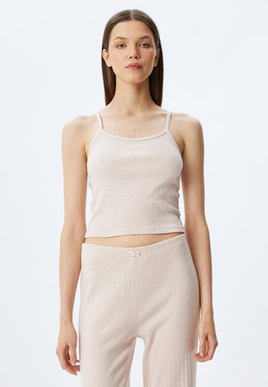 Helles rosa geripptes Tanktop mit dünnen Trägern, kombiniert mit passenden Hosen, die ein dezentes Muster und eine Kordelzugdetails am Bund aufweisen.