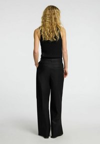 Black wide-leg trousers with a smooth texture, featuring back welt pockets and a tailored fit, designed for a sleek silhouette.