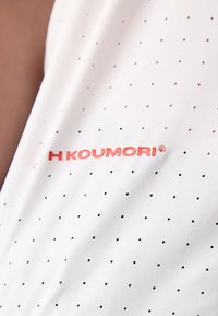 White textile featuring small black polka dots. "H.KOUMORI" logo in bold red font prominently displayed. Smooth, lightweight material.