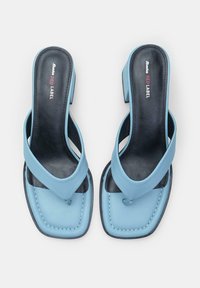 Light blue slip-on sandals with a squared toe, black insole, and cross straps; features contrasting white stitching detail.
