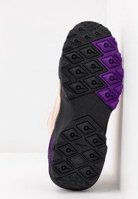 Semelle de chaussure de trail running avec motifs hexagonaux noirs et violets, équipée d'une surface texturée antidérapante et du logo « Hexalite ».
